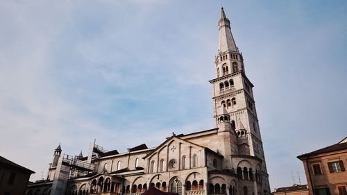 Low angle view of church and buildings against cloudy sky