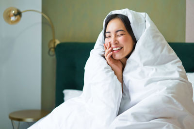 Portrait of young woman sitting on bed at home