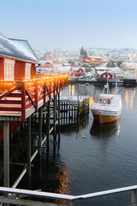 Boats moored in river by buildings against clear sky