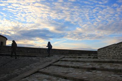 Low angle view of people on steps against sky