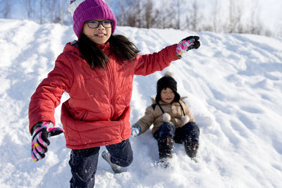 Siblings playing in snow during winter