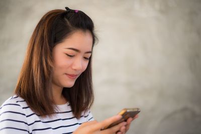 Smiling young woman text messaging on smart phone