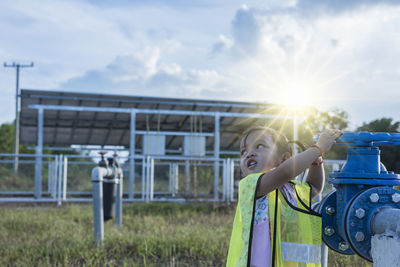 Rear view of man photographing on field against sky