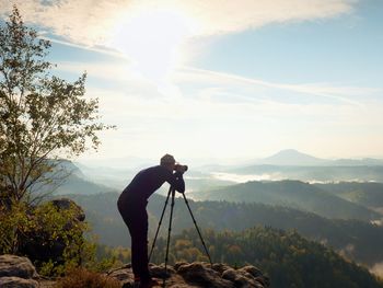 Man photographing on mountain against sky