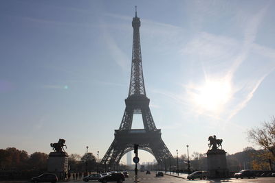 Cars on street by eiffel tower against sky