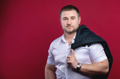 Portrait of young man standing against red background