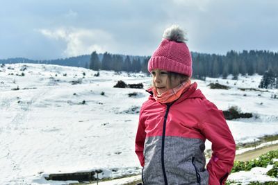 Portrait of boy standing on snow covered landscape during winter