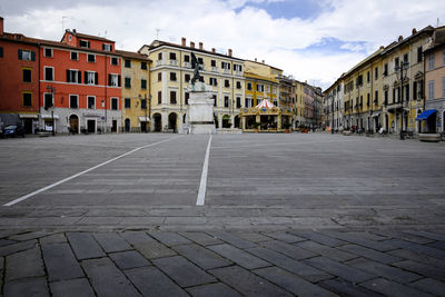 Road by buildings in city against sky