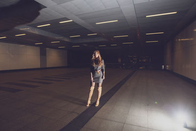 Woman standing in illuminated subway