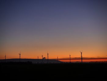 Silhouette of wind turbines on field during sunset