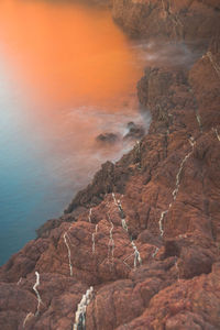 Rock formation in sea against sky during sunset