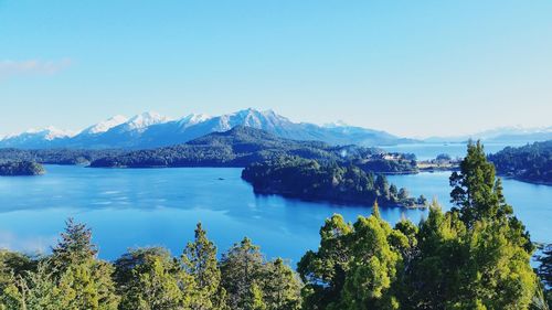 Scenic view of lake and mountains against clear blue sky