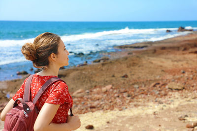 Woman with backpack at beach against sky