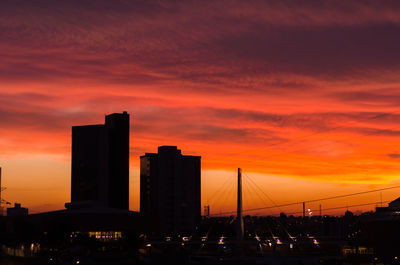 Silhouette of buildings against cloudy sky during sunset