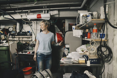 Female owner smiling while standing by coffee maker at auto repair shop