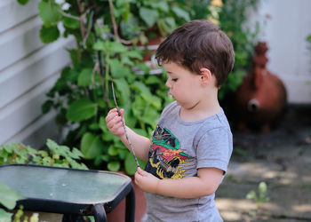 Curious toddler is playing with objects in the backyard.