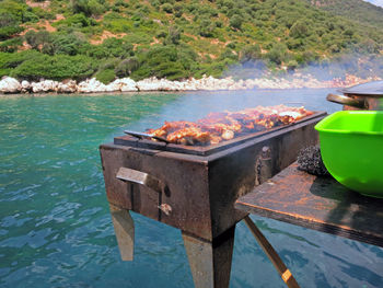 High angle view of meat on barbecue grill at lake