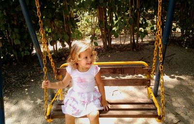 Smiling girl sitting on swing at park