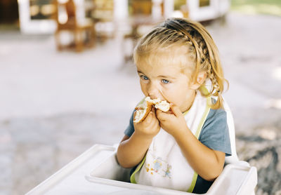 High angle view of girl eating food while sitting on high chair