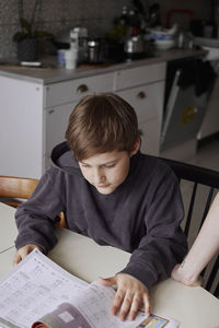 Boy sitting at table and doing homework