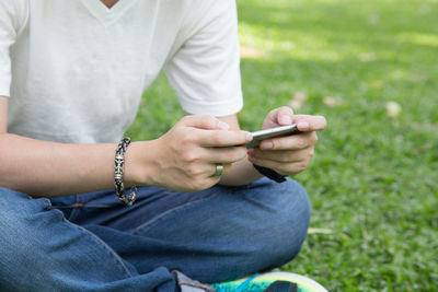 Close-up of man using mobile phone in grass