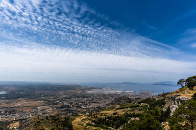 Aerial view of city by sea against blue sky