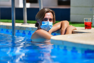 Portrait of shirtless man with mask swimming in pool