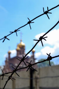 Low angle view of barbed wire fence against church