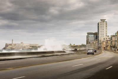 Cars on road against cloudy sky