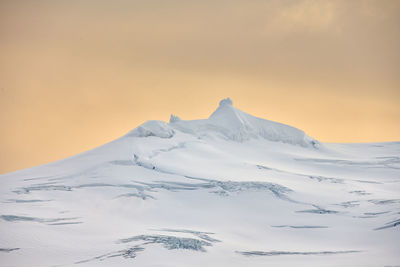 Snowy mountain against sunset sky