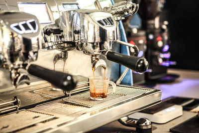 Coffee maker pouring drink in cup at cafe