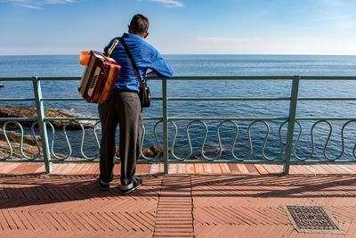 Rear view of man looking at sea against sky