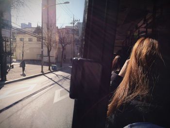 Rear view of woman sitting by window in bus