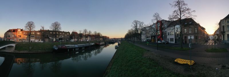 Boats moored in canal amidst buildings against sky in city