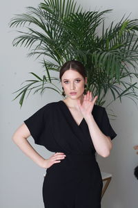 Portrait of young woman standing against plants