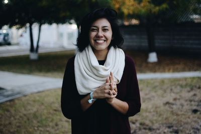 Portrait of happy young woman wearing scarf standing at park