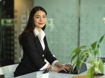 Portrait of smiling businesswoman using laptop at office