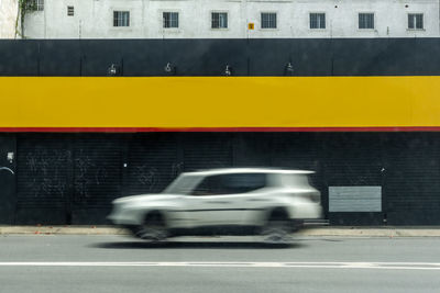 Blurred motion of yellow car on road