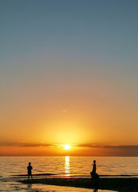 Silhouette people on beach against sky during sunset