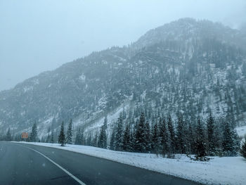 Road by mountains against sky during winter