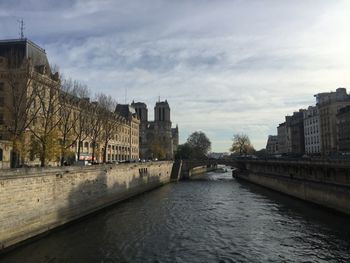 Bridge over river amidst buildings in city against sky