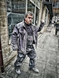 Full length portrait of man standing against building