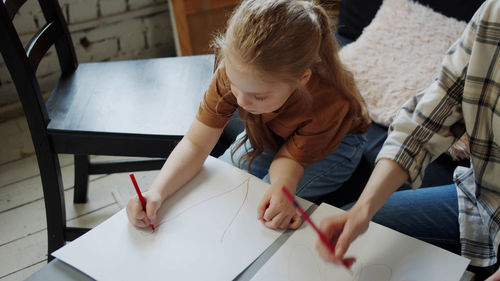 High angle view of mother and daughter drawing on paper