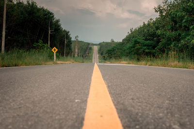 Surface level of road by trees against sky