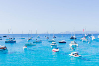 Sailboats moored in sea against clear sky