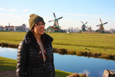 Smiling young woman standing on field against sky