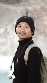 Portrait of young woman standing against wall
