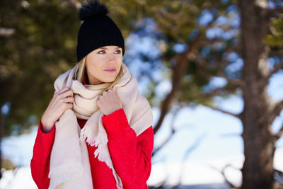 Portrait of woman standing by tree during winter