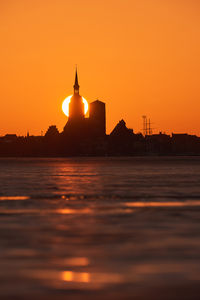 Scenic view of sea against orange sky at sunset