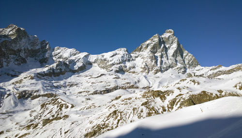 Scenic view of snowcapped mountains against clear blue sky